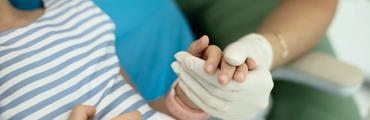 A dentist holds a young patient's hand during a dental emergency appointment
